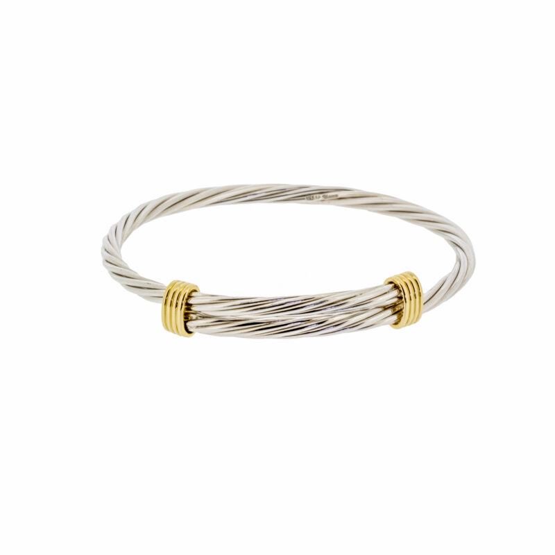 This silver and 18 carat yellow gold slider bangle comprises of six intertwined silver strands and one 18 carat gold strand. The 18 carat gold 'kiss' or 'X' end terminals make this bangle a truly eye-catching piece. The perfect combination of silver and 18 carat yellow gold creates a unique and distinctive piece of jewellery, perfect for any occasion. The intricate silver strands have been twisted to create a unique and individual design. The 18 carat gold end terminals add a touch of sophistication and elegance, creating a timeless piece that can be worn with any outfit. The bangle is a perfect example of combining modern and traditional elements to create something new and unique.